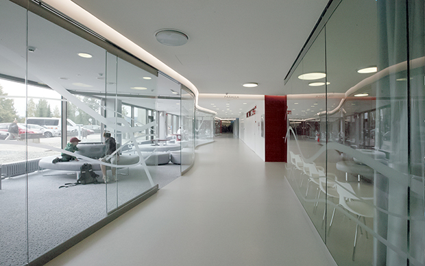Partanen & Lamusuon suunnittelema KYSin näyttenoton kaareutuva lasiseinä päästää luonnonvalon sisään | The curved glass wall in KUH’s sample collection area, designed by Partanen & Lamusuo, lets natural light in.