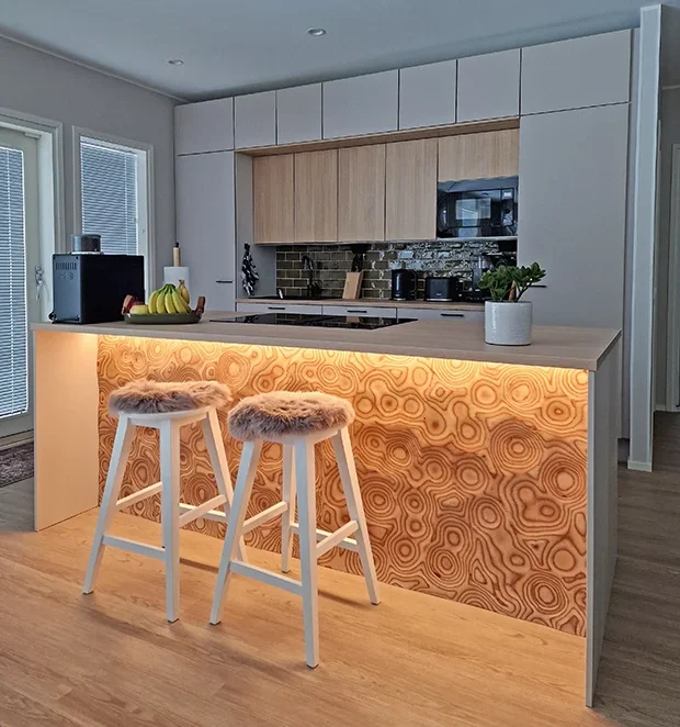 Keittiösaarekkeen pöytälevyn alle asennettiin valaisimet, joiden lämpimän sävyinen valo nostaa Palad Veistos™, keittiösaarekeen esiin. | Lighting installed beneath the countertop highlights the Palad Veistos™ surface. 